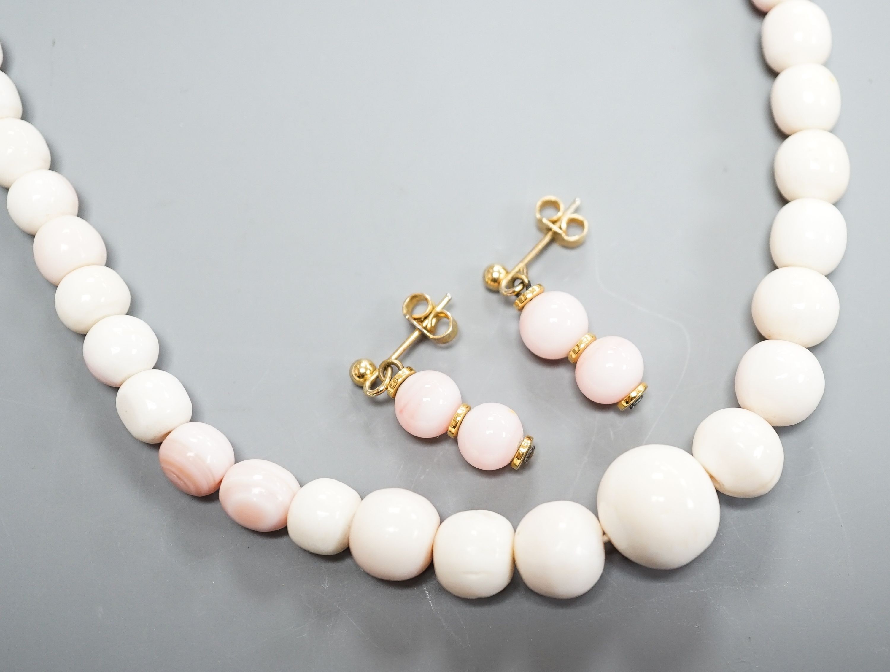 A single strand graduated bleached coral bead necklace, 51cm, gross 43.5 grams and a pair of 750 yellow metal and bleached coral earrings, 24mm, gross 4 grams.